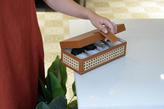 holding a brown wicker watch box with watches displaying watches and magnetic closure 