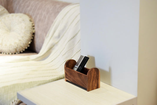 Wooden remote control holder on a shelf with a blurred sofa in the background
