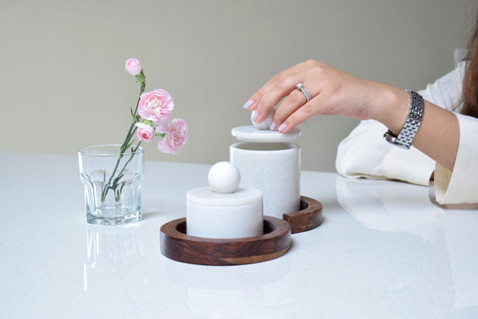 2 marble storage jars with wooden tray and lady holding it 
