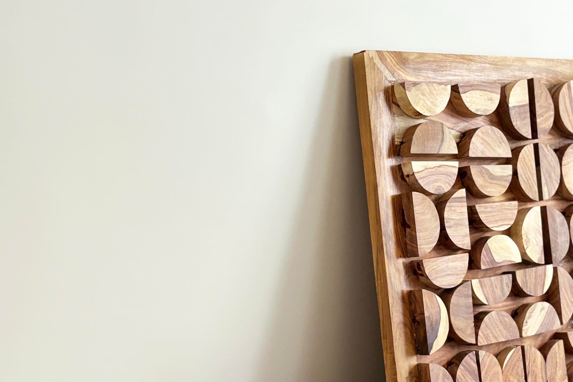 Wooden wall art with circular patterns on a plain background