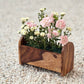 Wooden planter with flowers on a pebbled surface